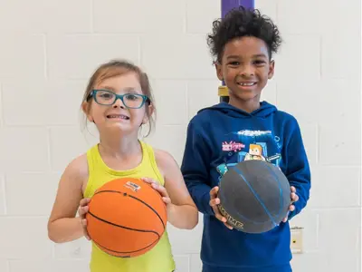 2 elementary children holding basketballs
