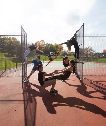 dance troup on a fence at a tennis court