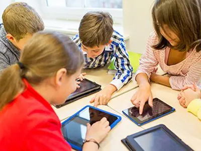 students sitting around a table working on tablets